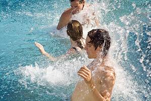 Drei Personen genießen eine anregende Wassermassage im Pool