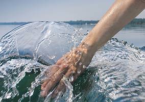 Hand durchstreift kraftvoll aufwirbelnd das klare Wasser eines S