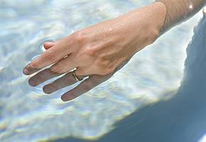 Hand die sanft in regenerierendes Wasser einer Therme eintaucht