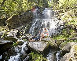 Paar sitzt auf Felsen vor einem Wasserfall und genießt die anre
