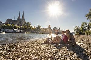 Junge Leute entspannen an der Donau mit Blick auf den Dom in Reg