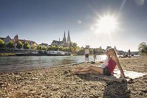 Junge Leute entspannen an der Donau mit Blick auf den Dom in Reg