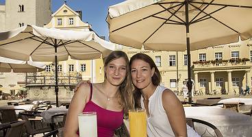 Zwei junge Frauen sitzen auf der Terrasse eines Restaurants in R