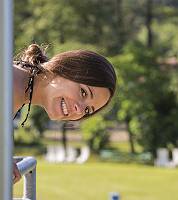Junge strahlende Frau beugt sich verschmitzt über Geländer