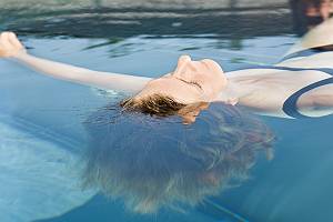 Frau lässt sich im Pool an der Wasseroberfläche treiben