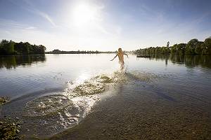 Junge rennt spritzend ins Wasser eines Sees