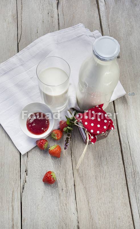 Milchflasche, Milchglas, Marmelade und Erdbeeren mit Leinentuch