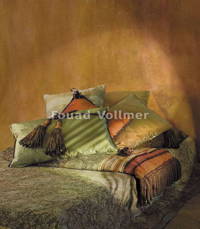 Schön hergerichtetes Bett mit farbigen Kissen und Decken