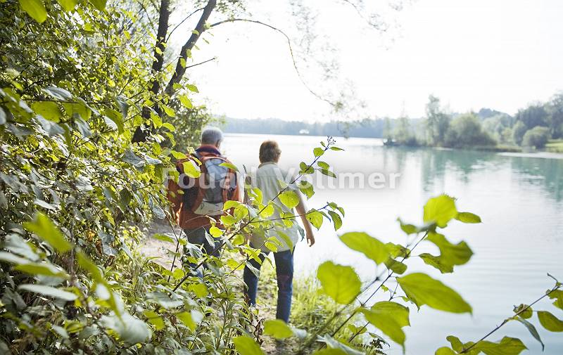 Älteres Paar geht entlang eines Sees spazieren