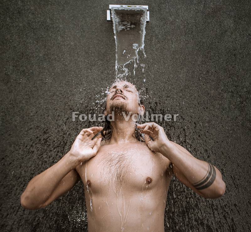 Kräftiger junger Mann beim Duschen