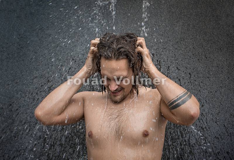 Kräftiger junger Mann beim Duschen