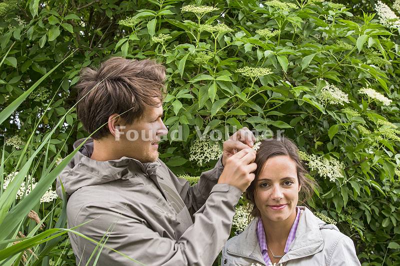 Mann steckt seiner Partnerin eine Holunderblüte ins Haar