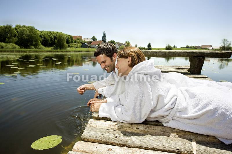 Paar liegt auf Holzsteg über dem Wasser