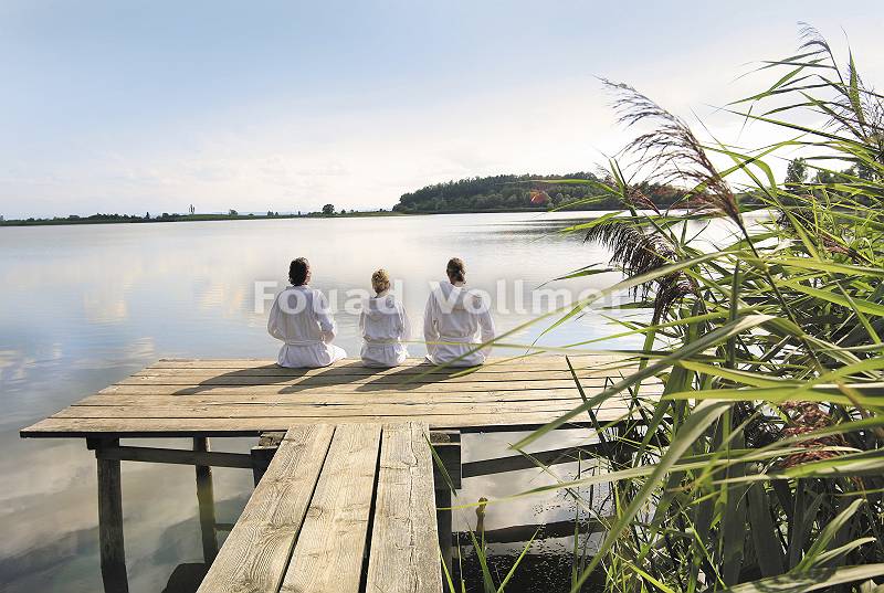 Drei sitzen im Bademantel am See