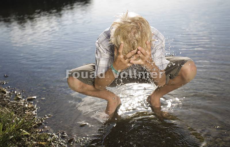 Blonder Junge erfrischt sich am See