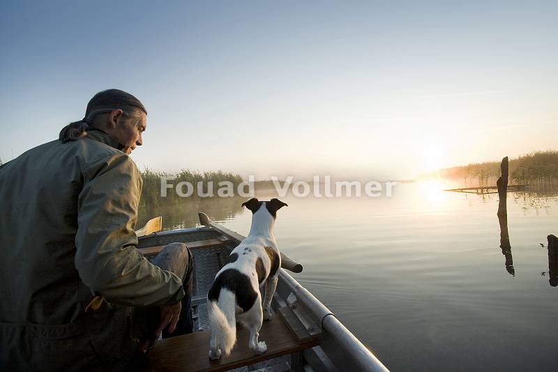 Mann mit seinem Hund auf einem Bootsausflug am Federsee