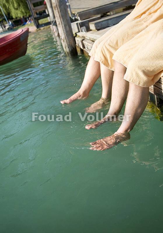 Zwei Personen hängen ihre Füße ins Wasser