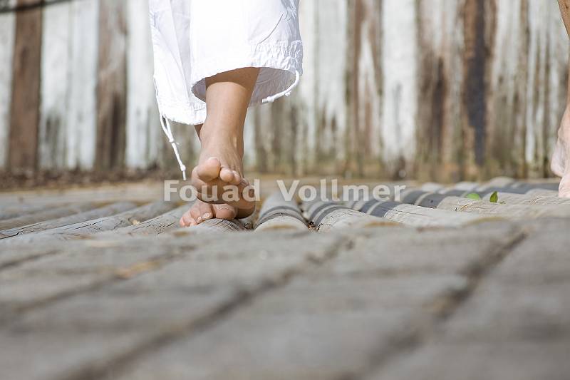 Eine Frau in weißer Hose erlebt einen Barfußpfad