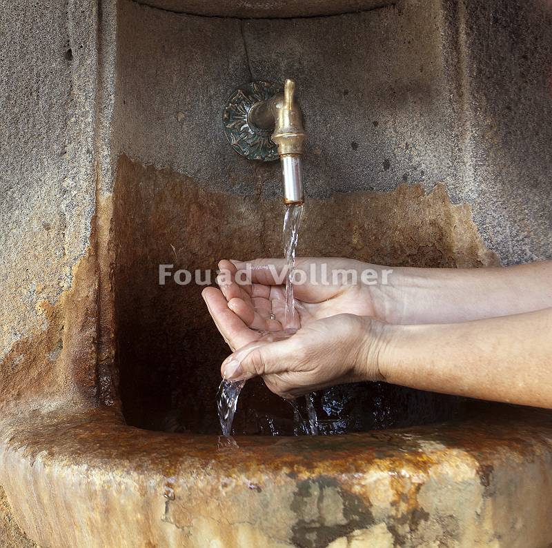 Hände fangen Wasser an altem Trinkbrunnnen auf