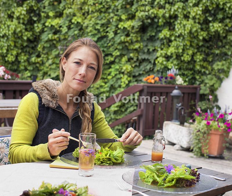 Frau isst Salat auf Terrasse